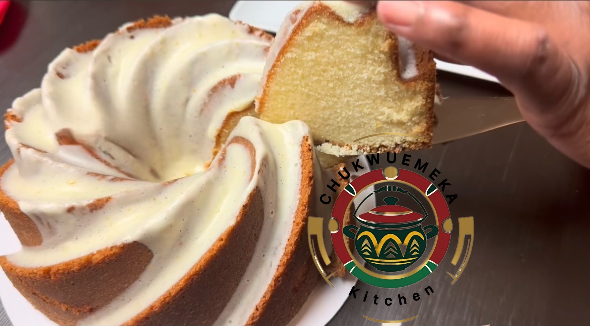 Bundt cake with white frosting being sliced, Chukwuemeka Kitchen logo visible